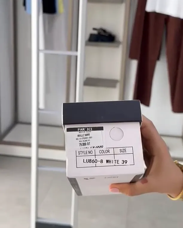 Boîte de chaussures étiquetée, présentée devant le portique antivol de la boutique.